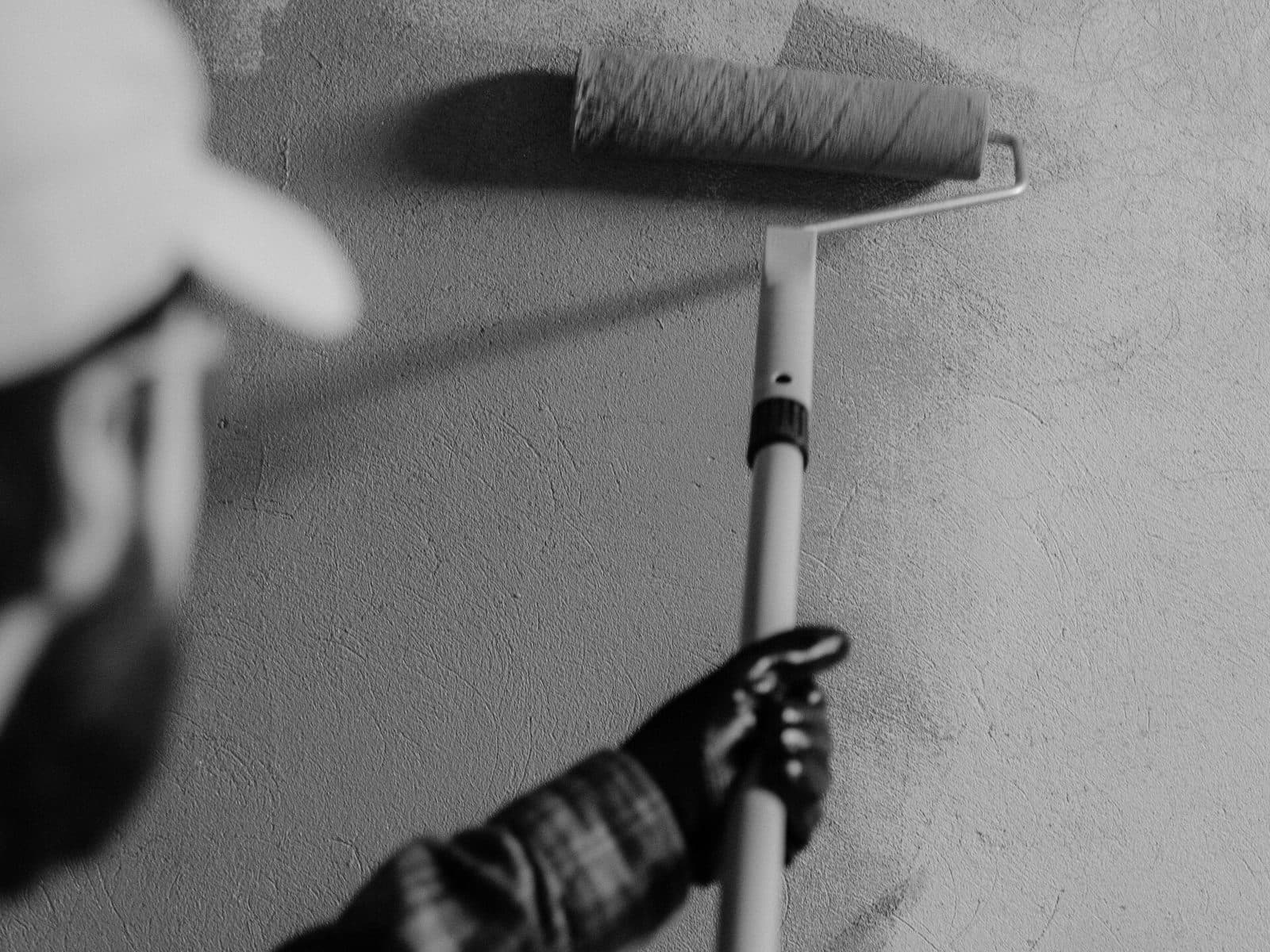 Illustrative photo: a painter rolling a prepared, patched wall