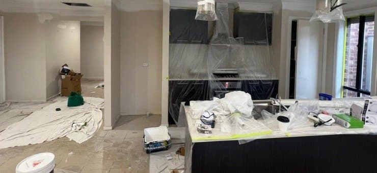 Open plan kitchen mid job, rangehood and benches wrapped, floors covered