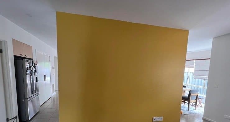 Finished mustard yellow feature wall beside the kitchen