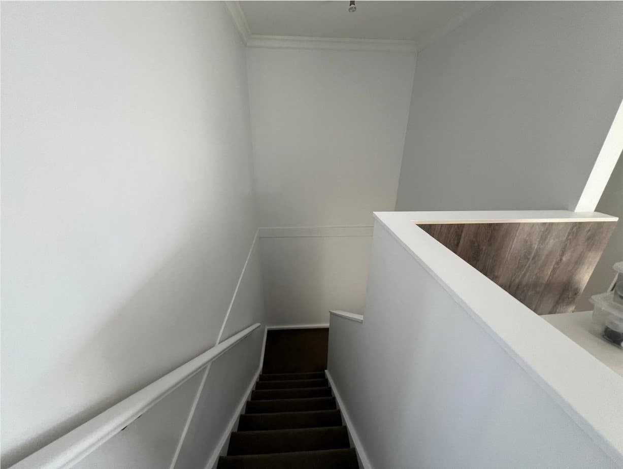 Stairwell repainted white with clean lines along the stair edge