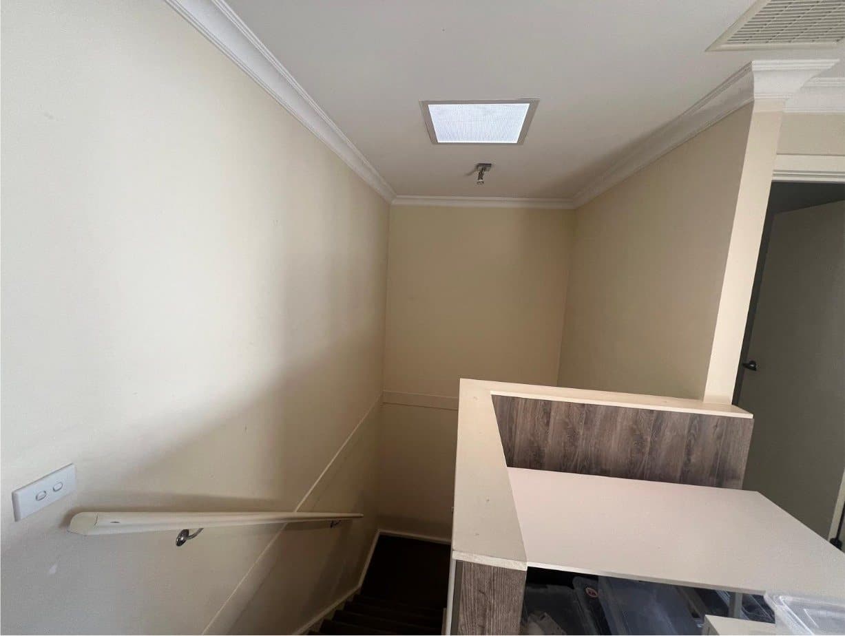 Stairwell with beige walls and handrail before repainting