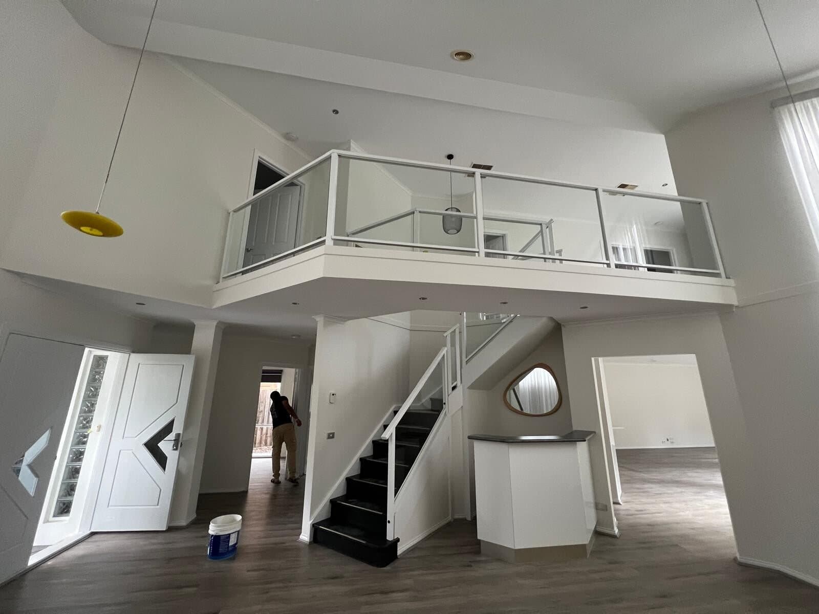 Painter at work in a double height entry with the staircase in view
